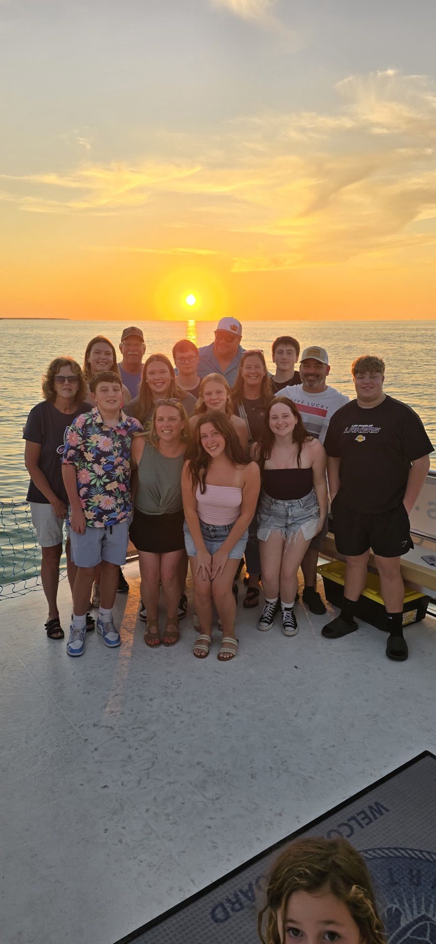 A large family group posed together on deck framed by a full golden sunset